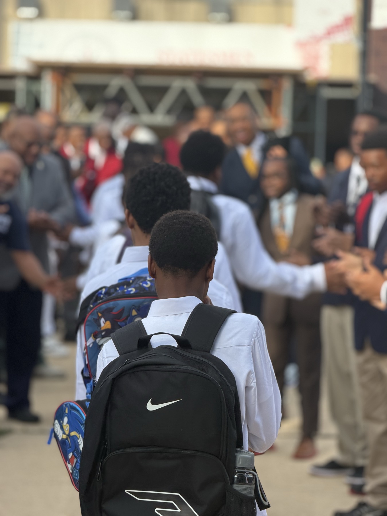 Boys arriving at school through a line of Black men cheering them on